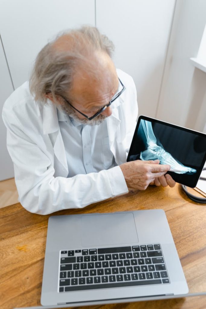 Senior doctor using tablet to explain X-ray results during an online consultation in a modern office.